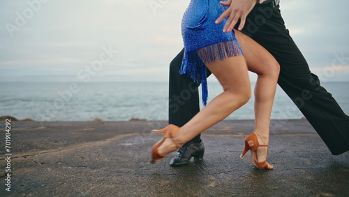 Feet unknown dance couple performing latin choreography on cloudy shore close up © stockbusters