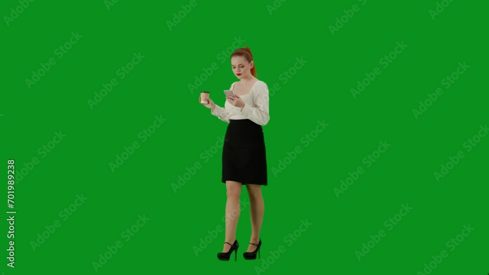 Portrait of attractive office girl on chroma key green screen. Woman in skirt and blouse walking drinking coffee from cup, texting on smartphone. Half turn. Portrait of attractive office girl on chroma key green screen. Woman in skirt and blouse walking drinking coffee from cup, texting on smartphone. Half turn.