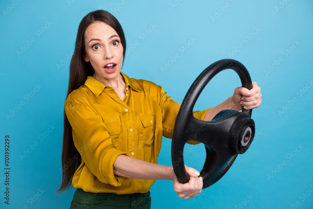 Photo of impressed funky lady wear yellow shirt riding auto steering wheel isolated blue color background Photo of impressed funky lady wear yellow shirt riding auto steering wheel isolated blue color background