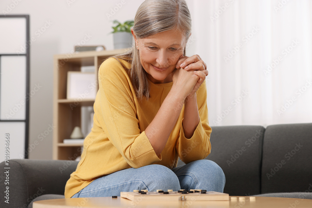 Thoughtful senior woman playing checkers at home Thoughtful senior woman playing checkers at home