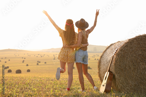 Hippie women near hay bale in field, back view photo