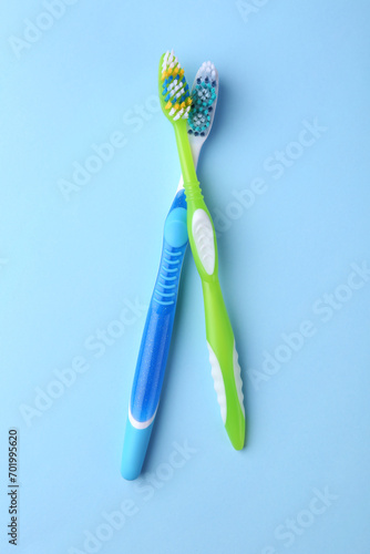 Two toothbrushes on light blue background  flat lay