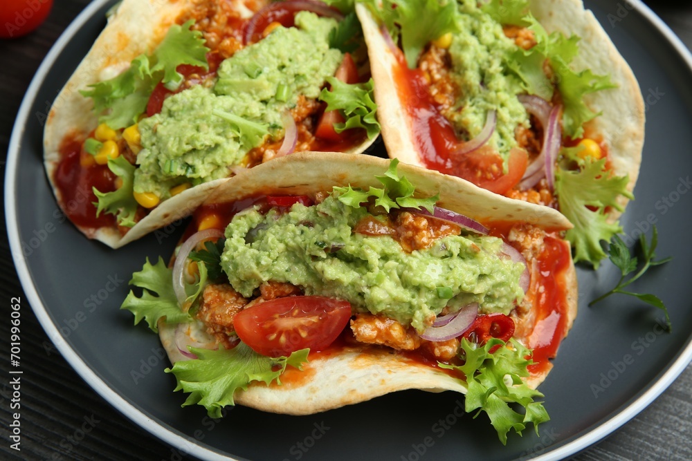 Delicious tacos with guacamole, meat and vegetables on table, closeup Delicious tacos with guacamole, meat and vegetables on table, closeup