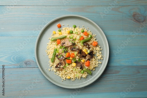 Delicious bulgur with vegetables and mushrooms on light blue wooden table, top view