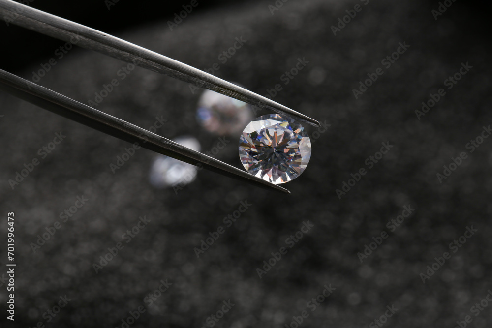 Tweezers with beautiful shiny diamond on dark background, closeup Tweezers with beautiful shiny diamond on dark background, closeup