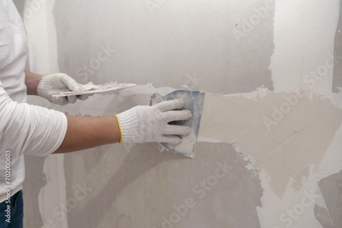 Plasterwork and wall painting preparation. Asian male applying filling drywall patch. photo