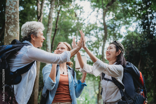 woman family walking in the forest to watching a bird in nature, using binocular for birding by looking on a tree, adventure travel activity in outdoor trekking lifestyle, searching wildlife in jungle
