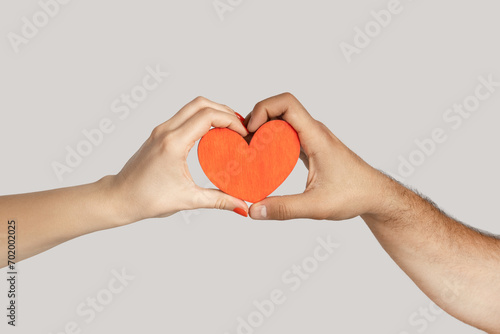 Closeup of multiracial female and male hands in heart shape  interracial relationship. Indoor studio shot isolated on gray background.