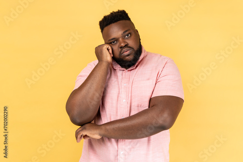 Φωτογραφία Portrait of sad upset man wearing pink shirt leans on hand, looking depressed, having indifferent gloomy expression has no energy