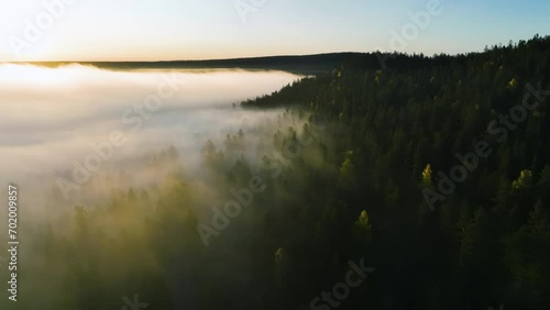 Aerial view along fog covered forest and hills, sunny fall morning in Lapland