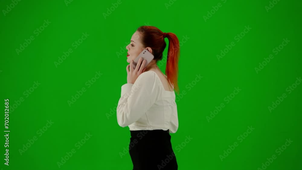 Portrait of attractive office girl on chroma key green screen. Woman in skirt and blouse walking talking on smartphone, positive face expression. Side view. Portrait of attractive office girl on chroma key green screen. Woman in skirt and blouse walking talking on smartphone, positive face expression. Side view.