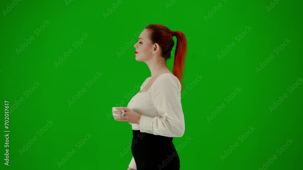 Portrait of attractive office girl on chroma key green screen. Woman in skirt and blouse walking smiling expression, drinking coffee from a mug. Side view. Portrait of attractive office girl on chroma key green screen. Woman in skirt and blouse walking smiling expression, drinking coffee from a mug. Side view.