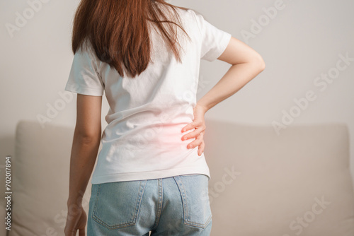 woman having back body ache during sitting on Couch at home. adult female with muscle pain due to Piriformis Syndrome, Low Back Pain and Spinal Compression. Office syndrome and medical concept photo