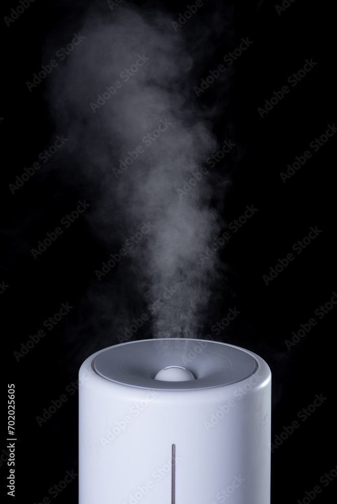 Household humidifier, ionization and air purification. White water vapor. Steam on a black isolated background. Household humidifier, ionization and air purification. White water vapor. Steam on a black isolated background.