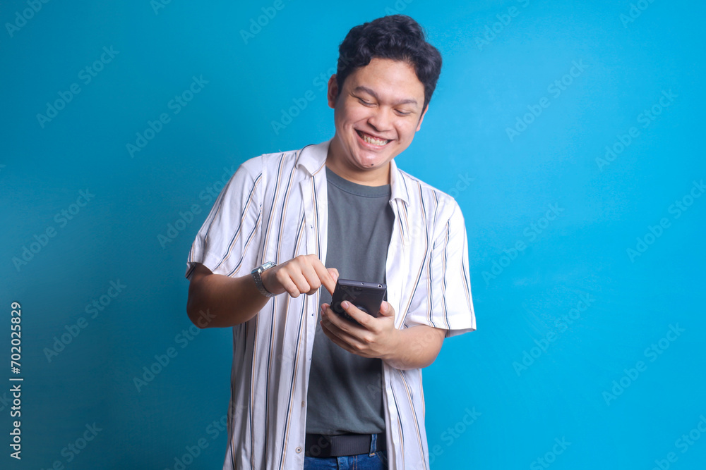 Happy young man using smartphone reading good news message or enjoying mobile application. Happy young man using smartphone reading good news message or enjoying mobile application.