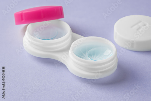 Cleaning contact lenses with solution liquid in case on pastel purple background