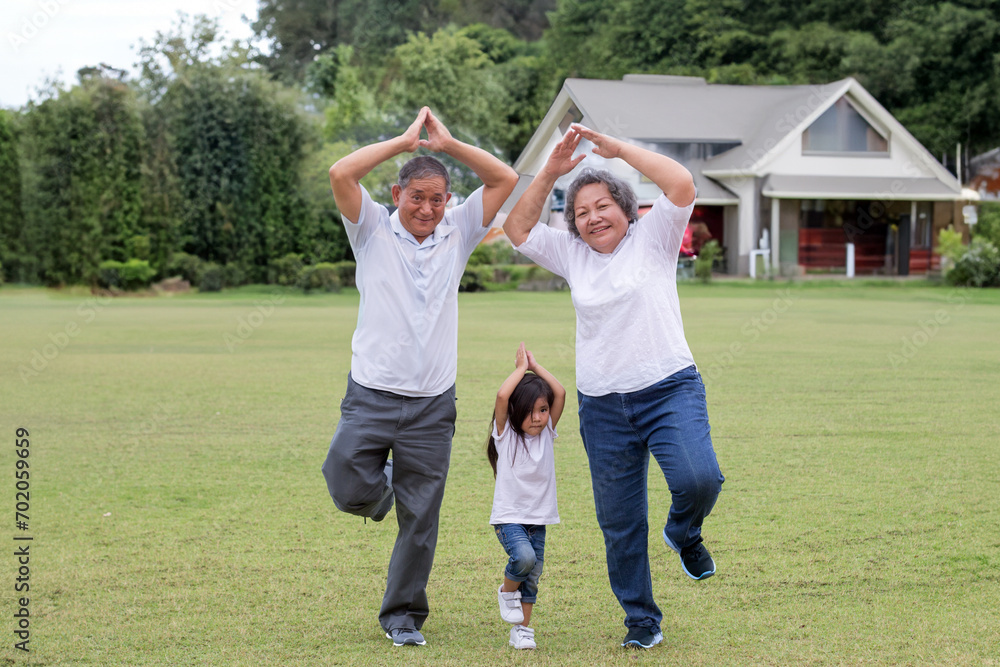 Healthy family with yoga poses exercising on the grass at grandpa and grandma house with granddaughter. lovely moment Healthy family with yoga poses exercising on the grass at grandpa and grandma house with granddaughter. lovely moment