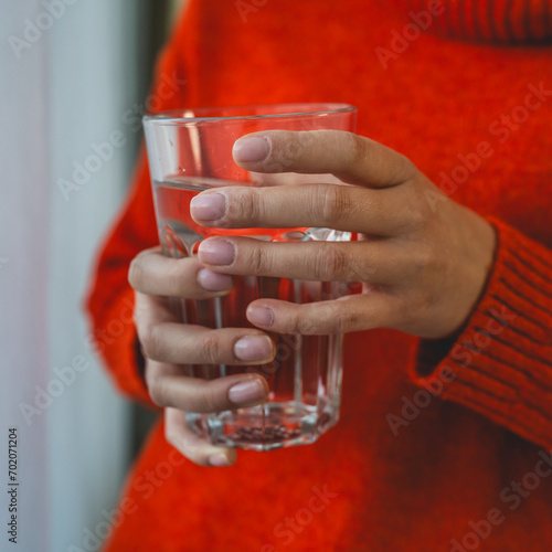 close up on midsection of unknown caucasian woman hold glass of water