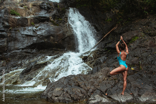 Young Woman in Swimsuit Practicing Yoga Near Waterfall in Rainforest