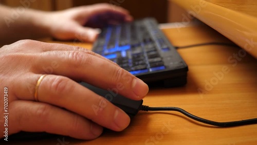 A person works at a computer using a mouse and keyboard. photo