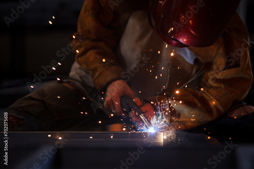 Heavy industry duty worker using a welding torch welds an iron steel in factory.