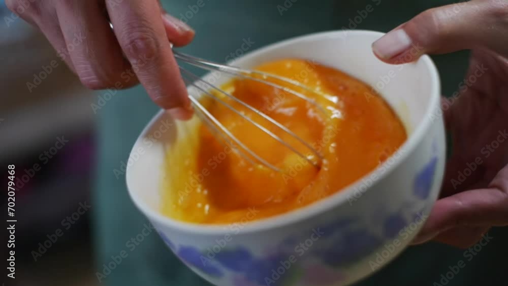 Raw orange egg yolks whisked and beaten in bowl by hand, filmed as close up in slow motion Raw orange egg yolks whisked and beaten in bowl by hand, filmed as close up in slow motion