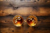 two glasses of liquid with ice cubes on a wooden surface