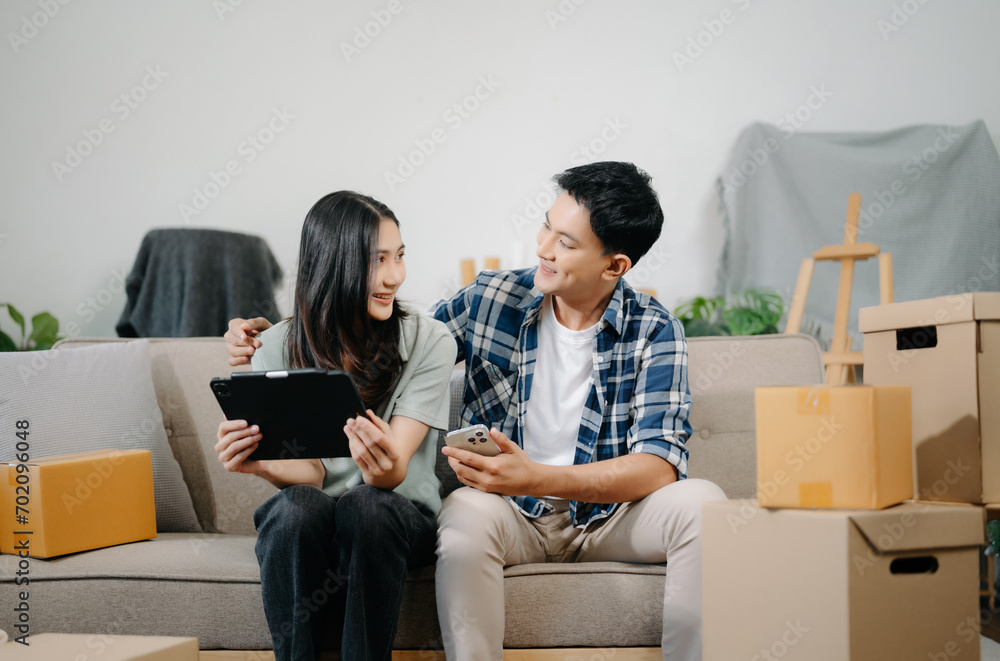 Young couple with big boxes moving into a new house, new apartment for couple, young asian man and woman helping to lift boxes on sofa . Young couple with big boxes moving into a new house, new apartment for couple, young asian man and woman helping to lift boxes on sofa .