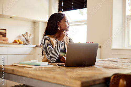 Businesswoman using a laptop in her kitchen photo