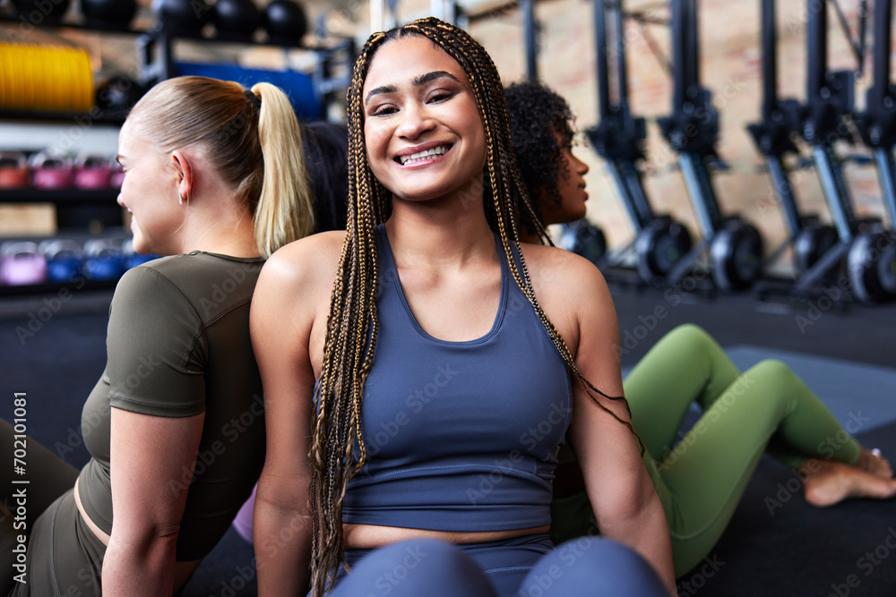 Smiling woman sitting with friends on a gym floor Smiling woman sitting with friends on a gym floor