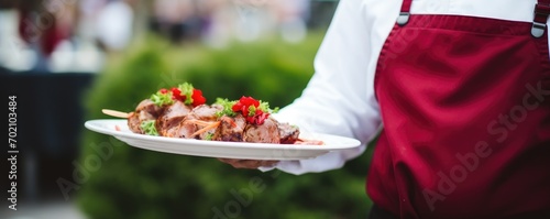 Waiter carrying plate with amazing meat dish. Catering service concept