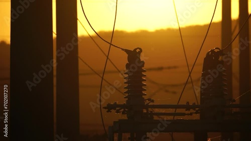 High voltage electric transformer station and distribution network at sunset. Power transmission lines on supports with ceramic insulators and transformers at large electrical distribution substation