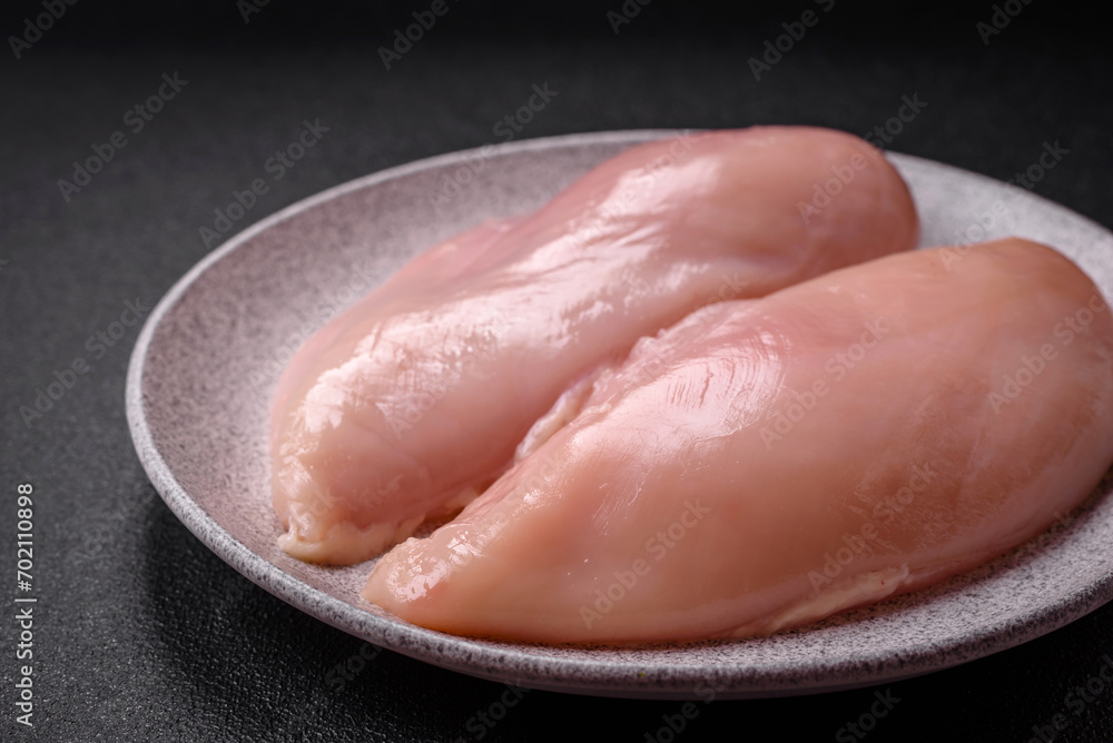 Fresh chicken fillet on a dark concrete table with spices and herbs Fresh chicken fillet on a dark concrete table with spices and herbs