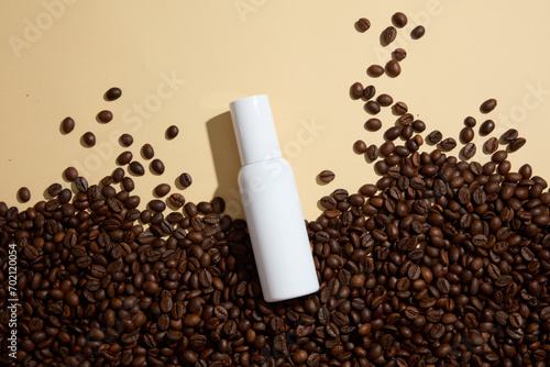 Blank background for advertising cosmetic product with coffee ingredient. Coffee beans decorated with white cosmetic bottle without label for design packaging. Top view photo