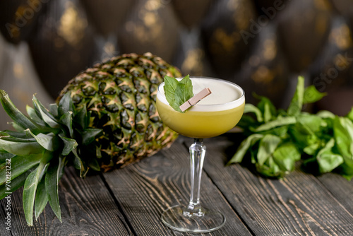 green cocktail on a wooden board with basil leaves and pineapple
