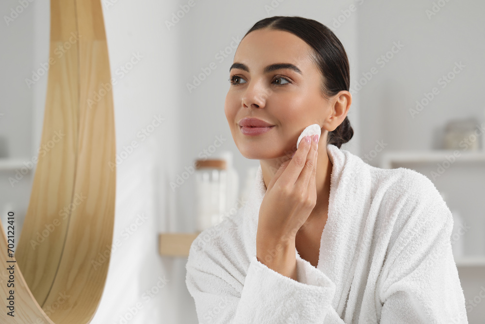 Beautiful woman removing makeup with cotton pad near mirror indoors, space for text Beautiful woman removing makeup with cotton pad near mirror indoors, space for text