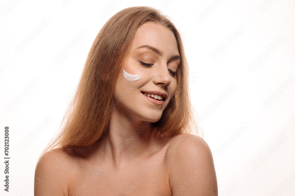 Beauty portrait of a beautiful blonde girl applying cream to her face on a white isolated background. Concept of cosmetology and skin care Beauty portrait of a beautiful blonde girl applying cream to her face on a white isolated background. Concept of cosmetology and skin care