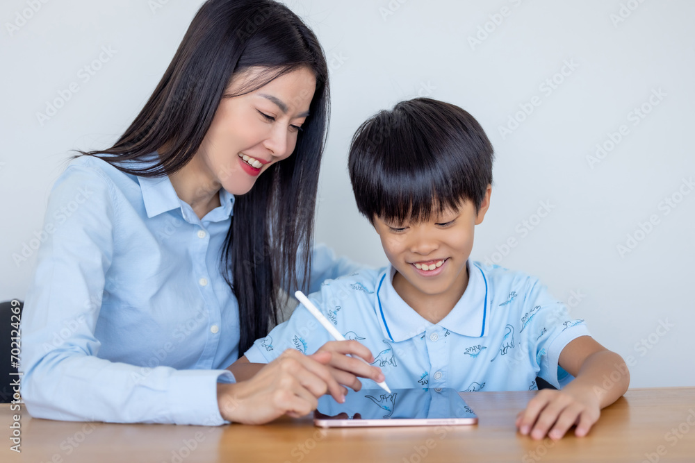 Teacher teaching kid boy student using digital tablet computer. Mother and her son use tablet computer. Woman teaching child son learning study tablet and doing homework. E-learning education concept. Teacher teaching kid boy student using digital tablet computer. Mother and her son use tablet computer. Woman teaching child son learning study tablet and doing homework. E-learning education concept.