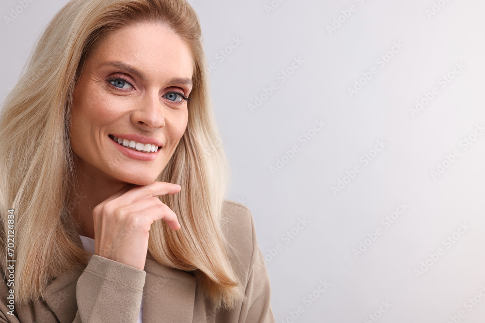 Portrait of smiling middle aged businesswoman on light grey background. Space for text Portrait of smiling middle aged businesswoman on light grey background. Space for text