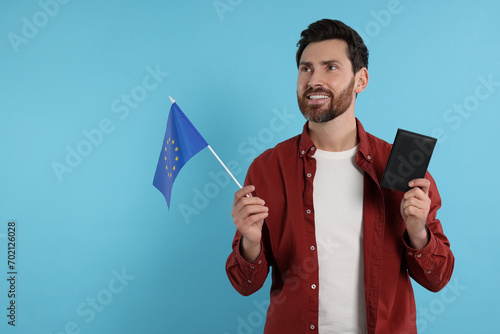 Immigration. Happy man with passport and flag of European Union on light blue background, space for text photo