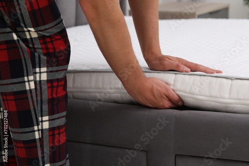 Man putting soft mattress on bed, closeup