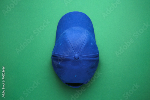 Stylish blue baseball cap on green background, top view