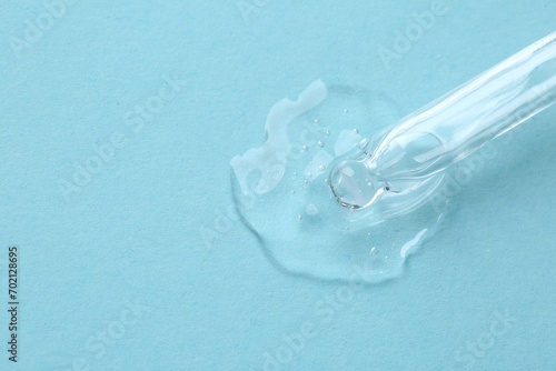 Dripping cosmetic serum from pipette onto light blue background, top view. Space for text © New Africa