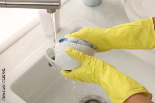 Woman washing cup at sink in kitchen, closeup