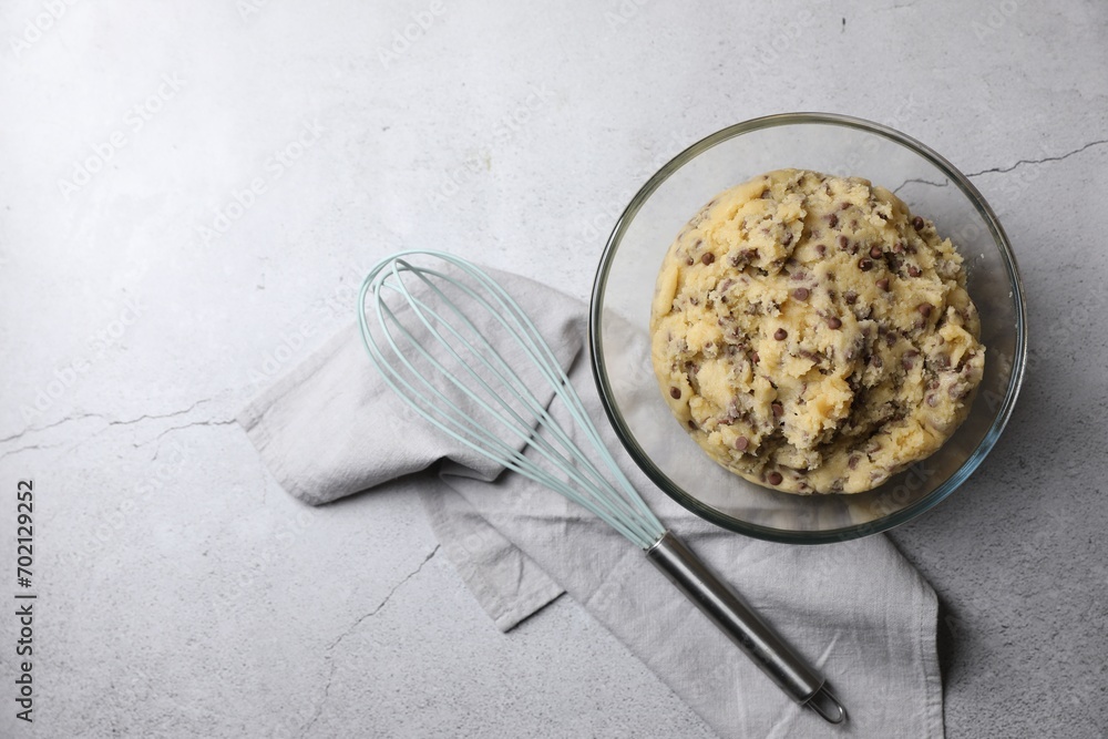 Chocolate chip cookie dough in bowl and whisk on light gray table, flat lay. Space for text Chocolate chip cookie dough in bowl and whisk on light gray table, flat lay. Space for text