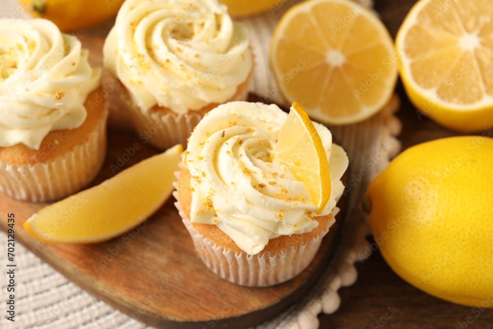 Tasty cupcakes with cream, zest and lemons on wooden table, closeup