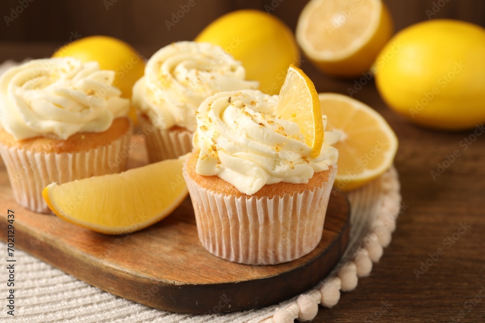 Tasty cupcakes with cream, zest and lemons on wooden table, closeup Tasty cupcakes with cream, zest and lemons on wooden table, closeup