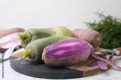 Purple and green daikon radishes on white textured table, closeup