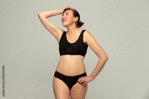 Attractive older woman 50 years old wearing stylish black underwear isolated on gray background. © Светлана Лазаренко
