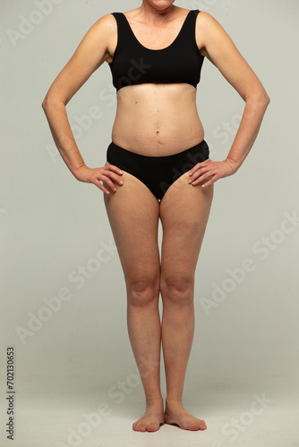 Full-length figures of a fifty-year-old woman in black lingerie on a gray background.